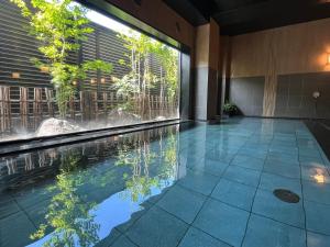 熊谷熊谷路途酒店 的一座房子里一个带瀑布的无边游泳池
