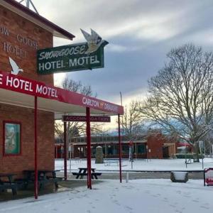 阿达米纳比Snow Goose Hotel的大楼旁边的雪地里的一个酒店汽车旅馆标志