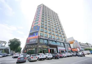 东莞City Comfort Inn Dongguan Tangxia Garden Street的停车场内有车辆停放的高楼