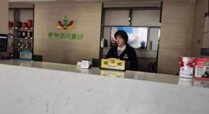 苏州GreenTree Alliance Hotel Jiangsu Suzhou Xiangcheng Distrcit Dongqiao的坐在商店柜台的女人