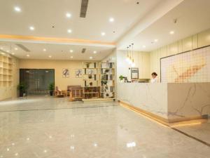 苏州GreenTree Inn Express Suzhou Luzhi Ancient Town Scenic Area Xiaoshi Road的站在大厅柜台的女人