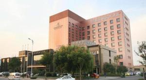 青岛Qingdao Danube International Hotel的一座大型建筑,前面有汽车停放