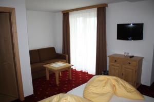 圣安东阿尔贝格Hotel Garni Dorfblick的酒店客房配有床、沙发和电视。