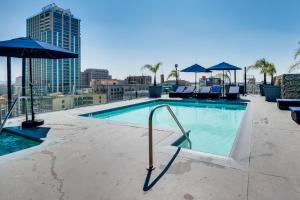 洛杉矶Downtown Los Angeles Condo with Rooftop Pool Access的一座大楼内的游泳池,配有椅子和遮阳伞