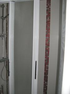 莫桑克斯拉皮蒂特芒格斯度假屋的浴室设有淋浴门,浴室设有瓷砖墙