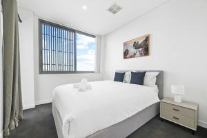 悉尼2BR Luxury Stay in Ultimo的白色的卧室设有一张大床和一个窗户