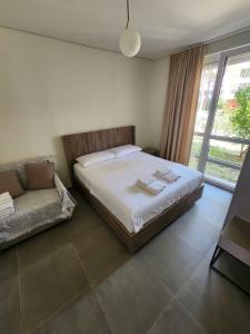 都拉斯SanPietro Relax Apartment的一间卧室配有一张床、一张沙发和一个窗口