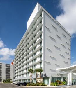 迈阿密DoubleTree by Hilton Miami North I-95的停车场里树木繁茂的大型白色建筑