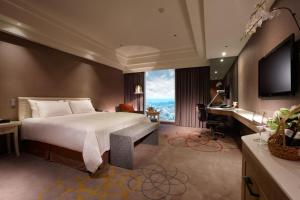 新竹新竹老爺酒店的一间卧室配有一张床、一张书桌和一台电视