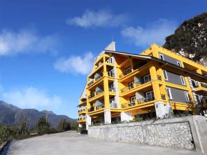 萨帕Aliana Boutique Sapa Hotel & Spa的山丘上的黄色建筑,背景是山脉