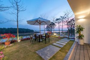 Phúc YênĐại Lải Resort - Lake view villa的庭院配有桌椅和遮阳伞。