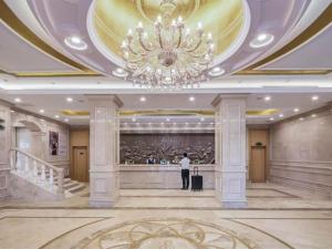 花都Vienna Hotel Guangzhou North Station Huaguoshan Metro Station的大堂里拿着手提箱,挂着吊灯的人