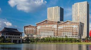 花都Guangzhou Rongchuang Jingshan Hotel的一座大建筑,靠近水体,有高大的建筑