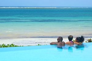 蒙巴萨航海家海滩度假酒店的一群人坐在海滩附近的游泳池里