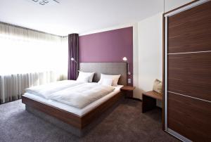 安德纳赫爱姆黑沃特斯图穆酒店的一间卧室设有一张大床和紫色的墙壁