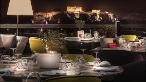雅典St George Lycabettus Lifestyle Hotel的用餐室配有桌椅和灯