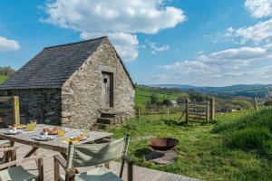 贝图瑟科伊德Snowdonia Glamping Holidays, Seren, Betws-y-Coed的石头建筑前的桌椅