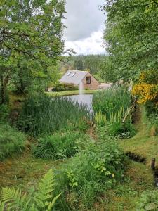 班科里Boghead Cottage: Holiday Cottage in Royal Deeside的一座房子前面的池塘,有一座建筑