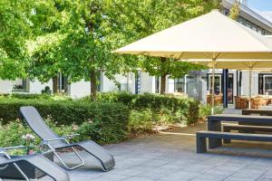 美因河畔法兰克福法兰克福机场城际酒店的一组椅子、一张桌子和一把伞