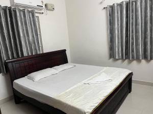 海得拉巴2 BHK Apartment Near AIG & ISB Gachibowli的卧室内的一张床位,卧室设有两个带窗帘的窗户