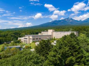 北斗市Grand Mercure Yatsugatake Resort & Spa的一座大建筑,有树木和山脉