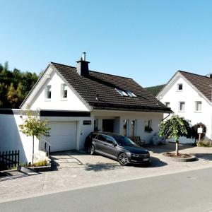 温特贝格Ferienwohnung "Apartment Sunlife Winterberg" 4 Sterne的停在白色房子前面的汽车