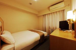 东京蒲田地产旅馆的酒店客房配有一张床和一张书桌及一台电视
