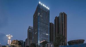 九江Grand Madison Jiujiang Yuexi Lake的一座高大的建筑,上面有灯