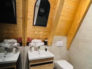 泰斯Vidis Chalet Hotel的一间带两个盥洗盆和木制天花板的浴室