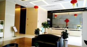 泉州Metropolo Hotel Jinjiang Wudian Wanda Plaza的大厅,有黑椅子,有人在柜台