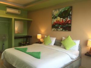 涛岛兄弟姐妹酒店的卧室配有带绿色枕头的大型白色床