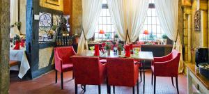 策勒Schifferkrug Hotel & Weinstube的一间带桌子和红色椅子的用餐室