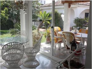 福恩吉罗拉Villa Bonita Fuengirola的门廊上设有带玻璃桌子和椅子的天井