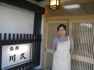 指宿市Family Ryokan Kawakyu with Showa Retro, private hot spring的女人站在门前