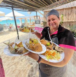 布兰卡滩Mandala Beach club的海滩上拿着两盘食物的女人