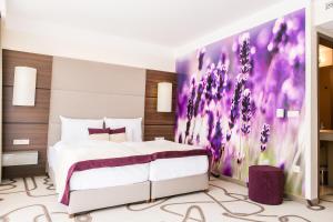 锡康达安比恩特阿罗马Spa酒店的一间卧室配有一张床铺,墙上挂着紫色绘画