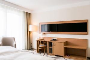 锡康达安比恩特阿罗马Spa酒店的酒店的客房,配有书桌和墙上的电视