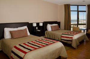 拉斯格路塔斯Hotel y Casino Del Río - Las Grutas的酒店客房设有两张床和窗户。