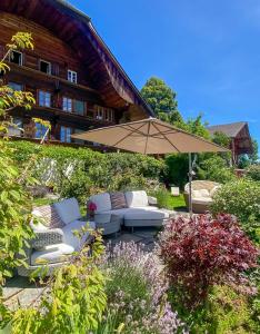 Erlenbach im SimmentalSwiss Mountain-Valley View Lodge的花园内带遮阳伞和沙发的庭院