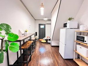 大阪Guest House KANOYA 2階建ての古民家貸切的厨房配有桌子和白色冰箱。