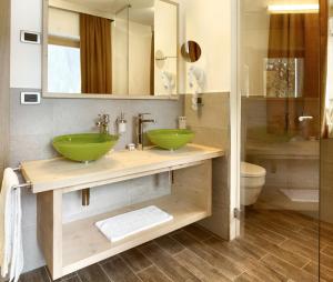 普雷达佐多彩家庭套房公寓酒店的一间带两个绿色水槽和淋浴的浴室