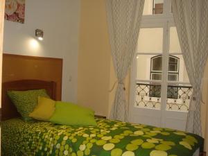 里斯本东旺娜桐宾馆的一间卧室配有一张带绿色棉被的床和窗户。