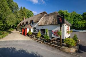 PewseyStunning 3 bedroom 3 bath self catering cottage near Stonehenge Avebury and Bath Great village pub的街道上茅草屋顶的建筑