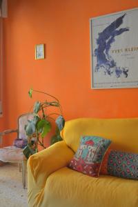 罗马4321 B&B Stazione Trastevere的橙色墙壁的房间里一张黄色的沙发