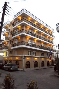 亚历山德鲁波利斯阿尔肯酒店的一座大型建筑,前面设有停车场
