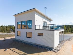 卡拉约基Seaside villa by paradise - Uusi korkeatasoinen huvila Kalajoki Hiekkasärkät的海滩上带阳台的白色小房子