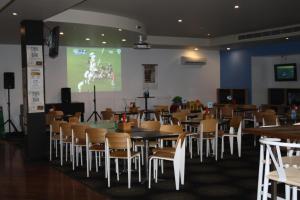 楠伯南博海滨汽车旅馆的一间带桌椅和屏幕的用餐室
