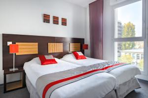 斯特拉斯堡斯特拉斯堡威尔逊拉格朗日公寓式酒店的一间卧室配有两张带红色枕头的床和窗户。