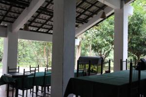 丹不拉Dambulu Oya Family Park的门廊上的用餐室配有桌椅