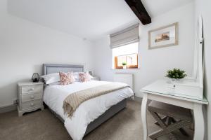 布由德利Hideaway Cottage Bewdley with parking near the River Severn的白色卧室配有床和书桌